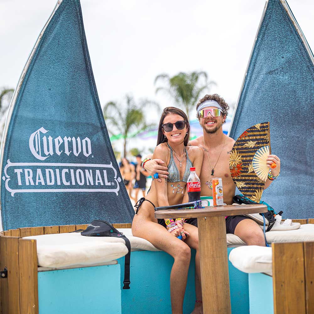 Two fans sitting down at Cuervo cabana