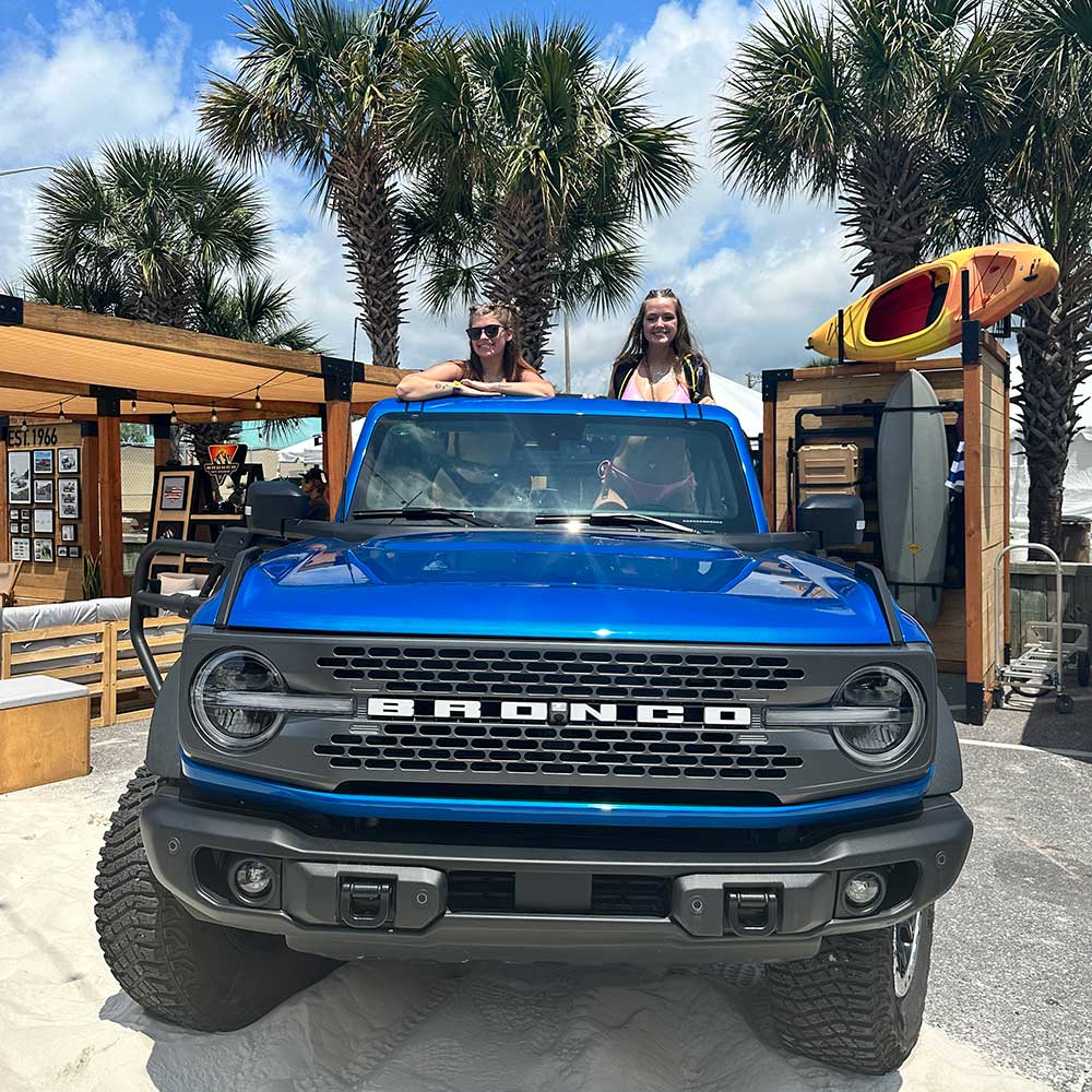 Two fans in a blue Ford Bronco