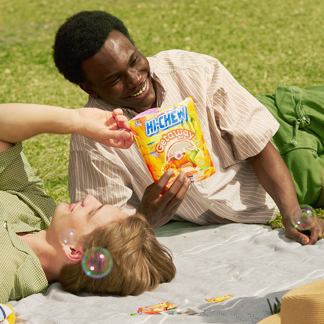 Fans on blanket laughing and eating HI-CHEW