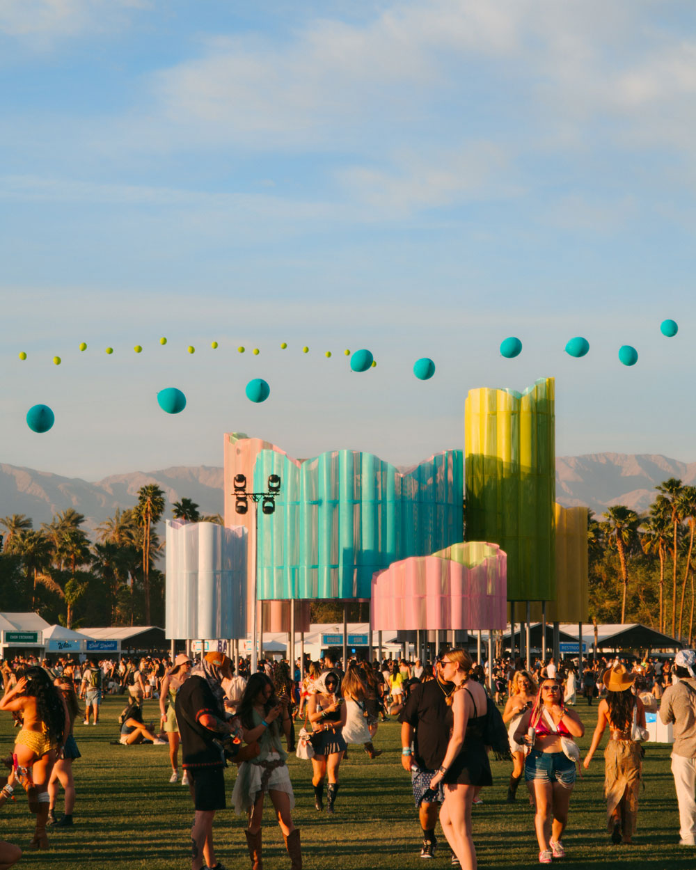 fans walking across field in front of art installations